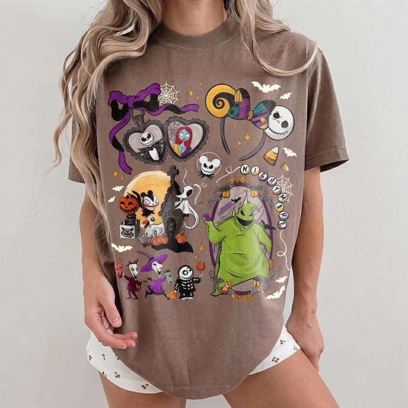 K&ouml;nnte beinhalten: Braunes T-Shirt mit einem farbenfrohen Grafikdesign mit Charakteren und Elementen aus "The Nightmare Before Christmas". Das Design umfasst Jack Skellington, Sally, Oogie Boogie und andere ikonische Bilder. Das Shirt hat einen Rundhalsausschnitt und kurze &Auml;rmel.