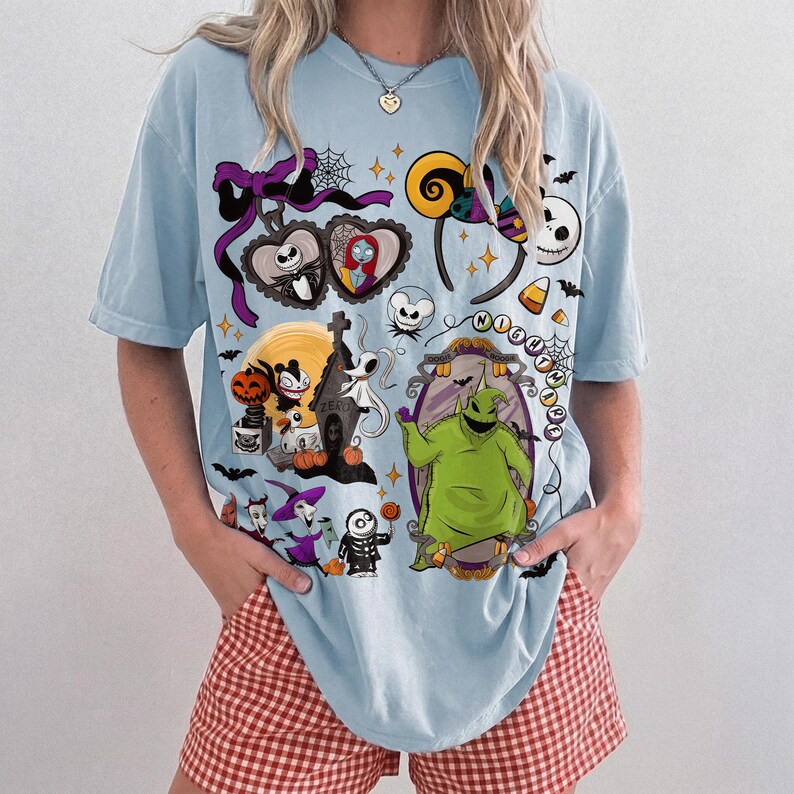 K&ouml;nnte beinhalten: Hellblaues T-Shirt mit einem Design von Halloween-Charakteren und -Elementen. Das Design zeigt Jack Skellington, Sally, Zero, Oogie Boogie und andere Charaktere aus The Nightmare Before Christmas. Das T-Shirt hat einen Rundhalsausschnitt und kurze &Auml;rmel.