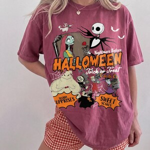K&ouml;nnte beinhalten: Ein bordeauxrotes Kurzarm-T-Shirt mit einem Grafikdruck von Charakteren aus Nightmare Before Christmas. Das Design enth&auml;lt den Text Nightmare Before HALLOWEEN Trick or Treat Candy Co, SUGARY SURPRISES und SWEET SCARES.