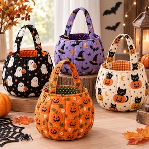 Könnte beinhalten: Vier gesteppte Halloween-Körbe aus Stoff mit Henkeln. Einer ist schwarz mit weißen Geistern und Kürbissen, einer lila mit Hexenhüten und Monden, einer orange mit Kürbisgesichtern und einer cremefarben mit schwarzen Katzen in Kürbissen.