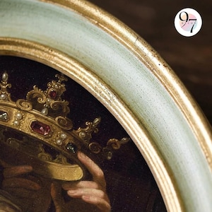 A close-up of the top right of an oval green and gold frame, showing the gold inner edge and part of a painting of a jeweled crown.