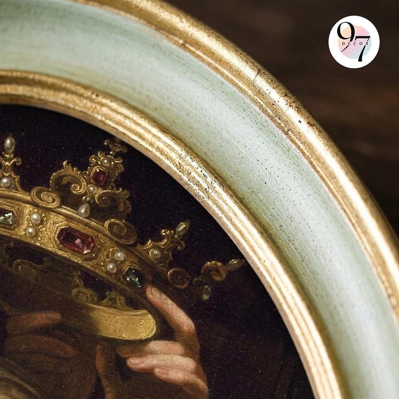 A close-up of the top right of an oval green and gold frame, showing the gold inner edge and part of a painting of a jeweled crown.