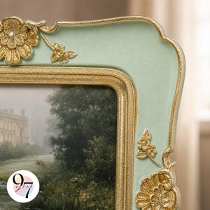 A close-up of the top right corner of a light green square picture frame with gold ornate details, showing part of a landscape painting.