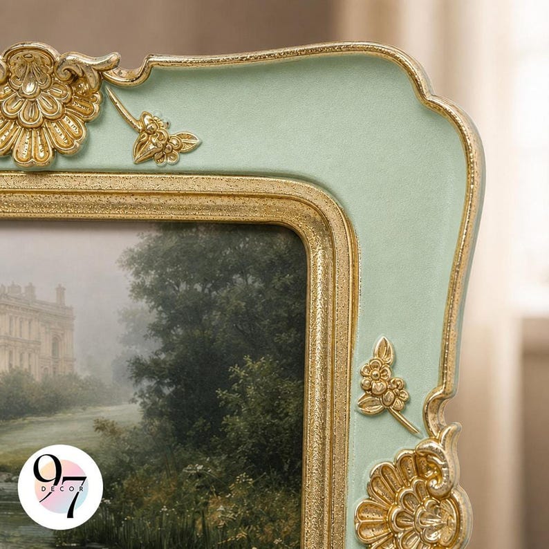 A close-up of the top right corner of a light green square picture frame with gold ornate details, showing part of a landscape painting.