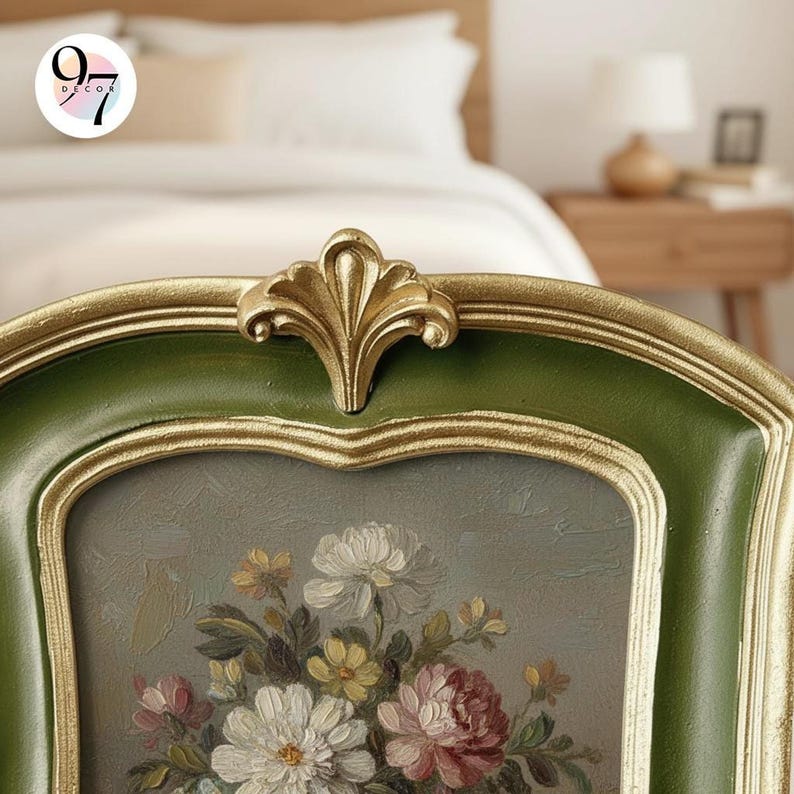 A close-up of the top of a rectangular green and gold frame with a floral painting, showing a decorative gold flourish.