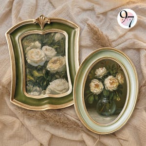 May include: Two framed paintings featuring white roses. The left frame is rectangular with a green and gold finish. The right frame is oval with a light green and gold finish. The paintings depict floral arrangements. A logo reads 97 DECOR.