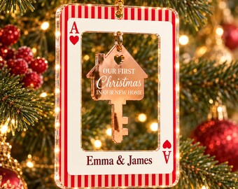 Könnte beinhalten: Ein rechteckiger Weihnachtsschmuck in Form einer Herz-Ass-Spielkarte mit roten und weißen Streifen. Im Rahmen hängt ein goldener, hausförmiger Schlüsselanhänger mit der Gravur "OUR FIRST Christmas IN OUR NEW HOME" und "Emma & James".