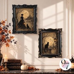 May include: Two framed wall art prints featuring gothic scenes with a full moon, a silhouette of a person in a long dress holding a lantern, and a black cat. Each print is encased in an ornate black frame with gold accents and intricate detailing.