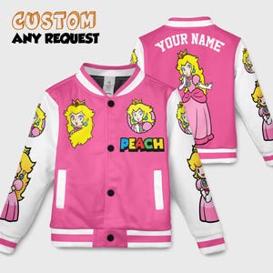 May include: Pink and white varsity jacket with a cartoon princess design. The jacket has the text "PEACH" on the front and "YOUR NAME" on the back. The sleeves and trim are white, and the jacket has black buttons.