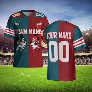 Puede incluir: Una camiseta de fútbol con un diseño de bloques de color verde azulado y granate. La camiseta presenta el texto "TEAM NAME" y "YOUR NAME" con el número "00". Mickey Mouse está representado en la parte delantera. Las mangas tienen rayas blancas y rojas.