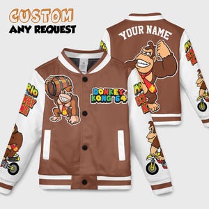 Peut inclure: Veste de baseball marron et blanche avec des graphismes de Donkey Kong. La veste a un corps marron, des manches blanches et un col et des poignets rayés. Le texte sur la veste comprend "CUSTOM ANY REQUEST", "DONKEY KONG 64" et "YOUR NAME".