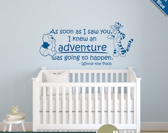 May include: A blue Winnie the Pooh and Tigger wall decal with the quote "As soon as I saw you, I knew an adventure was going to happen. - Winnie the Pooh". The decal is shown on a light blue wall above a white cot.