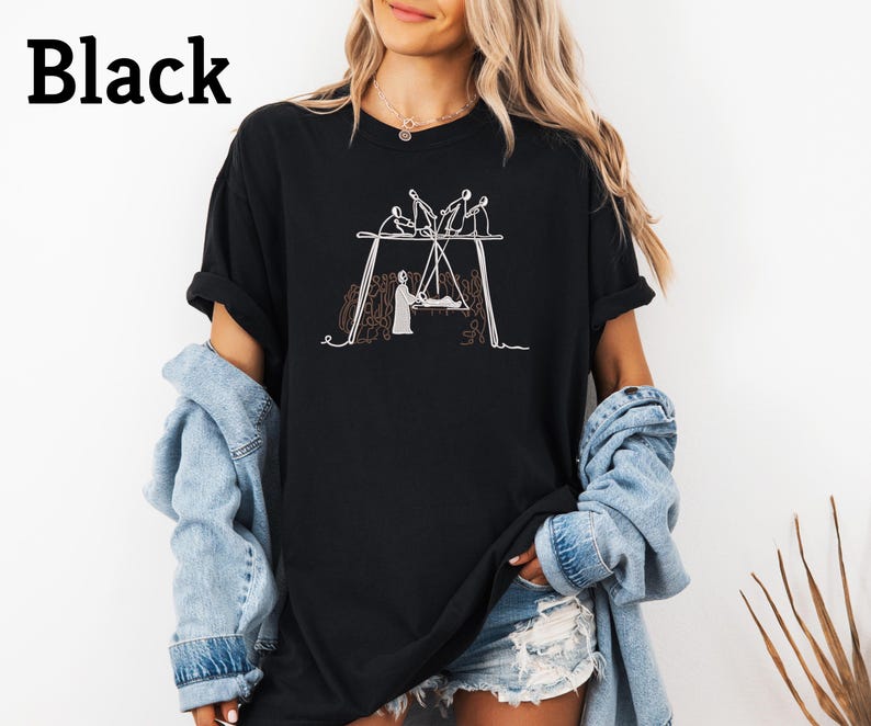 May include: Black t-shirt with a white line drawing of a swing set with figures. The word "Black" is printed in large, bold, black letters at the top left of the shirt. The shirt is a casual, oversized style.
