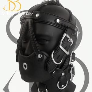 May include: Black leather head harness with multiple straps, buckles, and a muzzle. The harness features a padded design and metal hardware. The product is designed for adult use.