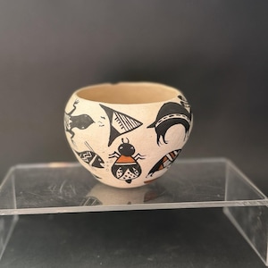 May include: A white ceramic mug with a black handle and the text "But First, Coffee" in a black, bold font. The mug is on a white surface.