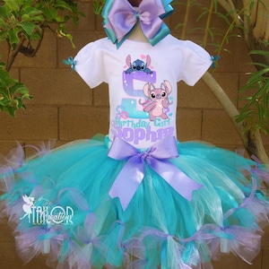 May include: A white t-shirt with a colorful graphic of Stitch and Angel from Lilo & Stitch, with the text "Birthday Girl Sophie". The shirt is paired with a turquoise and lavender tutu skirt, adorned with bows. A large matching bow completes the outfit.