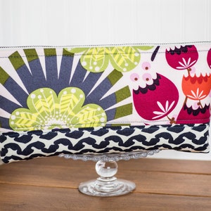 May include: A pink, green, and red floral print zippered pouch with a black and white geometric pattern on the bottom.
