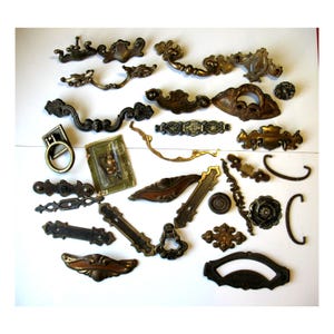 May include: A collection of antique brass and bronze drawer pulls and hardware. The assortment includes various shapes and sizes, from ornate handles to simple knobs, with a range of patinas and finishes. Ideal for furniture restoration or crafting projects.