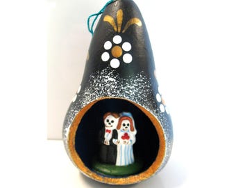 Ornement vintage en calebasse représentant un couple de mariés squelettes, sur le thème du Jour des Morts. Art populaire mexicain.
