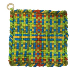 May include: A square, woven hot pad with a colorful pattern. The design features a grid of green, blue, yellow, and red threads. The edges are trimmed with a braided border and a wooden ring for hanging.