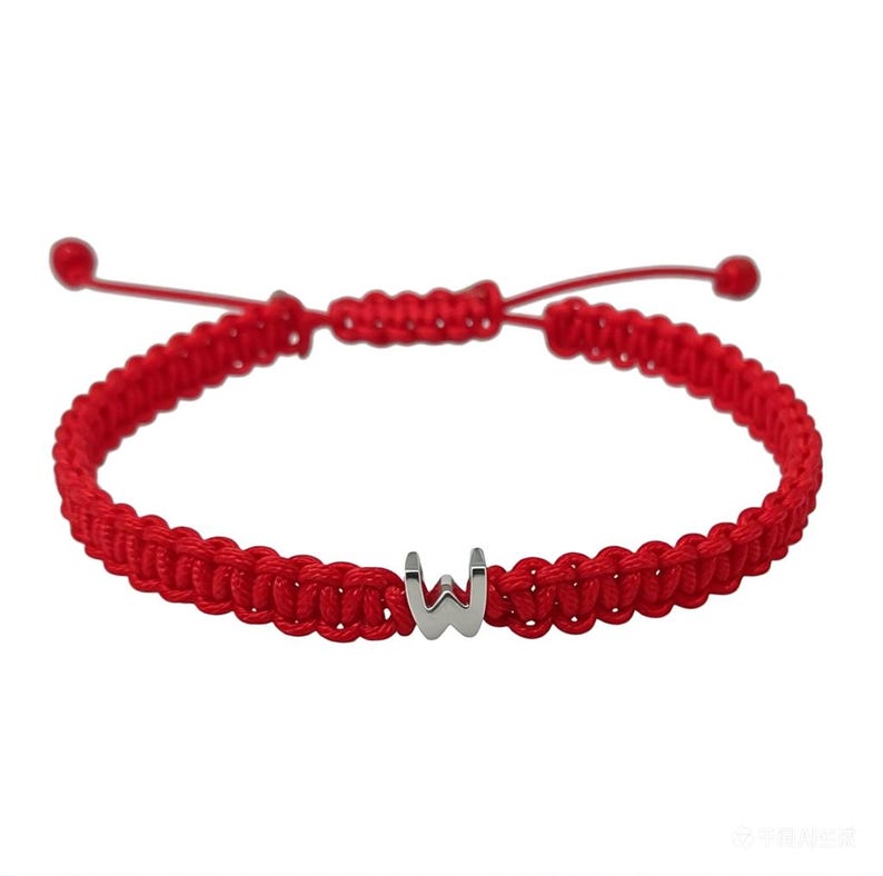 May include: Red braided bracelet featuring a silver letter "W" charm. The bracelet is adjustable with sliding knots and red cord. A simple and stylish accessory.