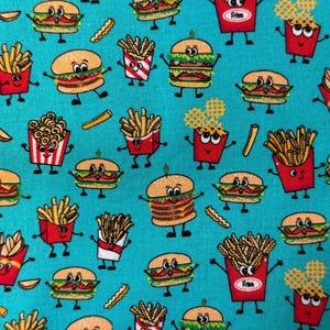May include: A teal fabric featuring a repeating pattern of cartoon hamburgers, french fries, and onion rings. The food items have smiling faces and are in red and white containers. The design is playful and colorful.