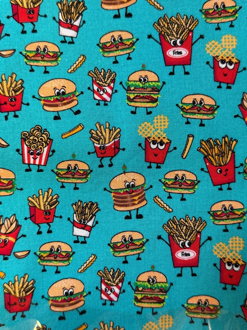 May include: A teal fabric featuring a repeating pattern of cartoon hamburgers, french fries, and onion rings. The food items have smiling faces and are in red and white containers. The design is playful and colorful.