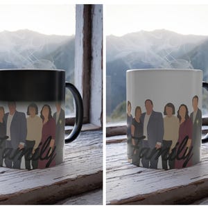 May include: A black and white color-changing mug with a family portrait design. The mug features a group of people and the word "Family" in a script font. The mug is on a wooden surface near a window.
