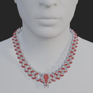 Puede incluir: Un collar plateado con detalles rojos, exhibido en un maniquí. El collar presenta un diseño de eslabones de cadena, con piedras preciosas rojas y un colgante central. El colgante tiene una forma distintiva, posiblemente un animal o un diseño abstracto.