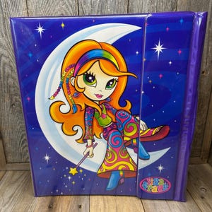 May include: A purple Lisa Frank binder featuring a cartoon girl with orange hair, a rainbow headband, and colourful clothing. The girl is seated on a crescent moon against a starry blue background. The binder has a purple spine and the Lisa Frank logo.