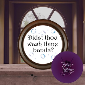 Könnte beinhalten: Ein runder, gerahmter Stickrahmen mit dem Text "Didst thou wash thine hands?" in schwarzer Schrift. Das Design umfasst blaue und violette Blasen. Ein violetter Kreis mit dem Logo "Thistlesword Stitchery" befindet sich neben dem Rahmen.