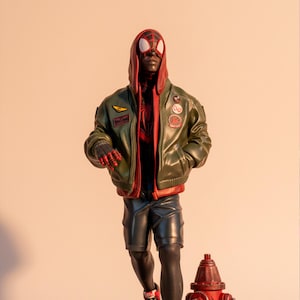 May include: A detailed figurine of Spider-Man Miles Morales in a dynamic running pose. He wears a green jacket, black shorts, and red and white sneakers. A red fire hydrant and a sewer grate base complete the scene.