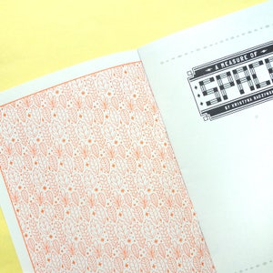 May include: A white book with an orange and white patterned cover. The title of the book is "A Measure of Space" by Kristina Baczynski.