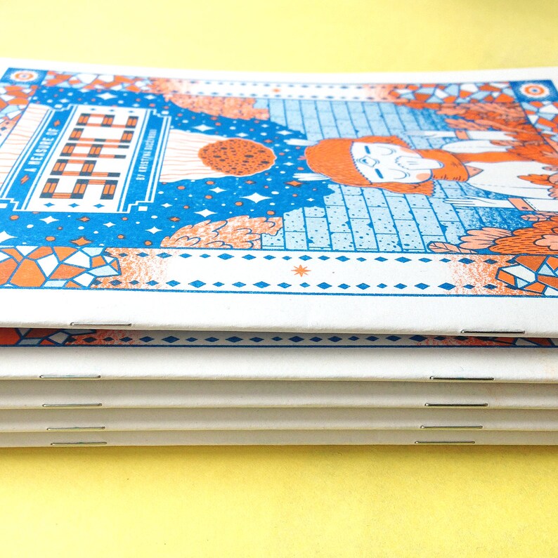 May include: A stack of four small, white, bound books with orange and blue covers. The cover features a colorful illustration of a person with a red beard and a blue background with stars. The title of the book is "A Leisure of Stitch" by Kristin Nicholas.