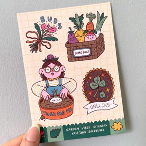 May include: A sheet of colorful stickers with a garden theme. Designs include a bouquet of pink flowers, a basket of smiling vegetables, a gardener planting a bulb, and a lucky charm. Text includes "BUDS", "SQUAD GOALS", "TUCK ME IN", and "UNLUCKY".