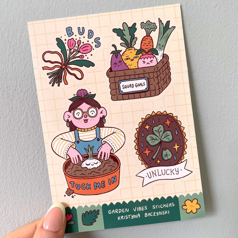 May include: A sheet of colorful stickers with a garden theme. Designs include a bouquet of pink flowers, a basket of smiling vegetables, a gardener planting a bulb, and a lucky charm. Text includes "BUDS", "SQUAD GOALS", "TUCK ME IN", and "UNLUCKY".
