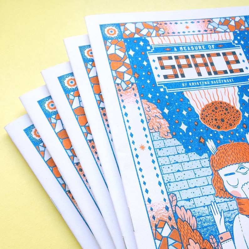 May include: A stack of five blue and orange illustrated zines titled "A Measure of Space" by Kristina Baczynski.
