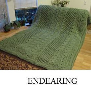 May include: Three knitted blankets with different patterns. The first blanket is purple with a wave-like pattern. The second blanket is green with a diamond pattern. The third blanket is white with a cable knit pattern.