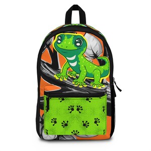 May include: A backpack featuring a cartoon green gecko on a branch against an orange background. The front pocket is bright lime green with a repeating pattern of black gecko footprints. The bag has black zippers, trim, and a top handle.