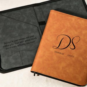 May include: A tan leather-look portfolio case with a zip closure, featuring the monogram DS and the name Deborah Stott on the front. The interior is dark grey with a pocket containing the text: Believe in your essence and your hidden gifts.