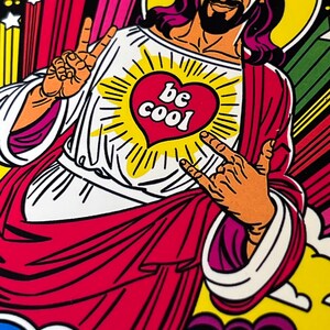 Może przedstawiać: Ilustracja w stylu pop-art przedstawiająca postać z aureolą, ubraną w białą szatę i czerwony płaszcz. Postać ma brodę i wykonuje gesty dłońmi. Na piersi znajduje się serce z napisem "be cool". Tło ma kolorowe paski i gwiazdy.