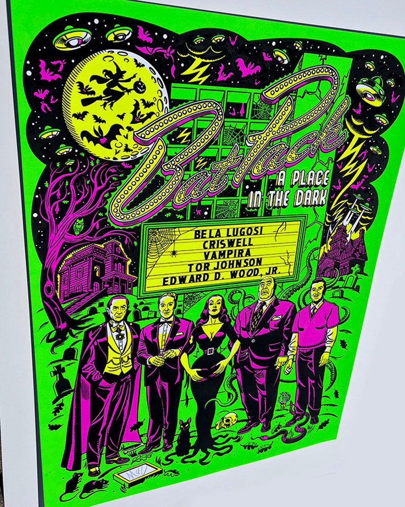 May include: A green and black poster with the title "Bat Pack: A Place in the Dark" featuring a group of actors from classic horror films. The actors include Bela Lugosi, Criswell, Vampira, Tor Johnson, and Edward D. Wood Jr.