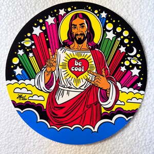 Może przedstawiać: Kolorowa, okrągła grafika przedstawiająca stylizowaną ilustrację postaci w czerwonej szacie i białej tunice, z długimi włosami i brodą. Projekt zawiera gwiazdy, promienie i tekst "be cool" w sercu.