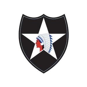 May include: A black shield-shaped emblem with a white star in the center. Inside the star is a profile of a Native American in red with a blue and white headdress. The number "2" is not visible. The emblem is set against a white background.