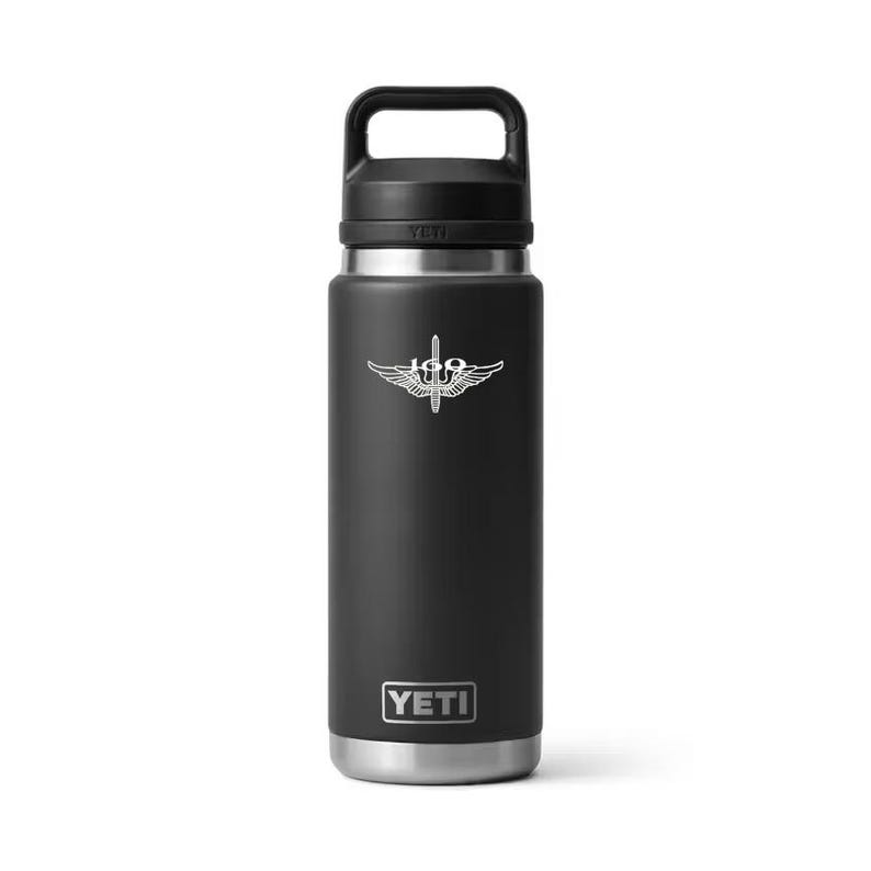 May include: A black insulated water bottle with a silver emblem and the brand name "YETI" at the bottom. The bottle has a black handle and lid. The emblem is a silver design of a winged object.
