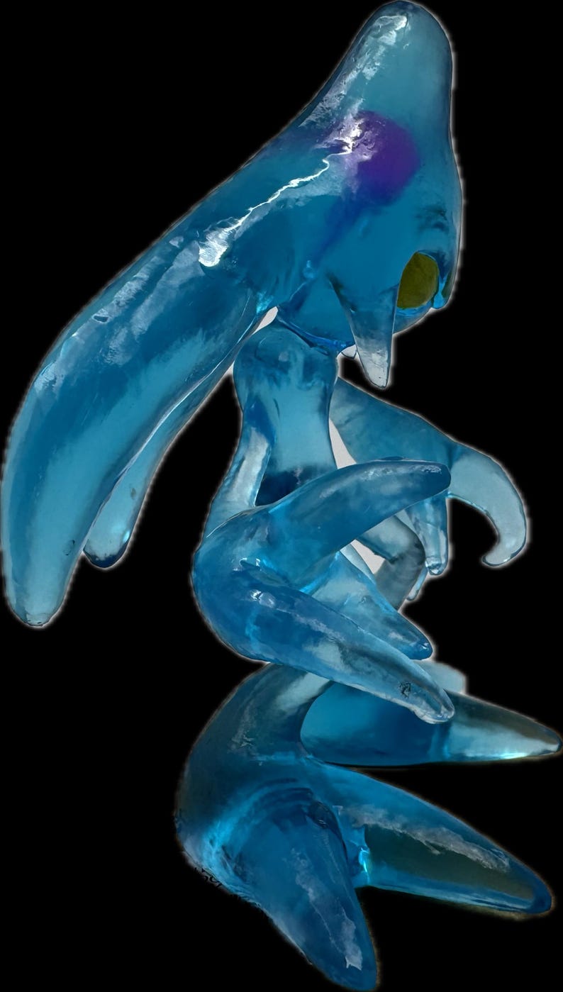 May include: A translucent blue sculpture of a creature with a flowing, amorphous form. The figure has elongated limbs and a head with pointed features. The sculpture has a smooth, glossy texture and is set against a black background.