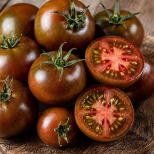 May include: A collection of whole and halved dark brown tomatoes with green stems. The tomatoes have a smooth, round exterior and a cross-section revealing a vibrant red and green interior with visible seeds and a star-shaped pulp structure.