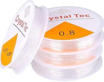 May include: Spools of clear, elastic beading cord. The spools have white labels with the text "Crystal Tec" and an orange triangle with the number "0.8". The cord is tightly wound on the spools, ready for jewelry making or other crafts.