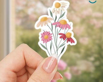 May include: A sticker featuring a bouquet of colorful flowers. The flowers have pink, red, and white petals with yellow centers. The sticker is held by a hand with a blurred background.