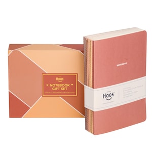 May include: A notebook gift set featuring a rectangular box with geometric orange and red patterns, labeled Hoos Notebook Gift Set. Beside it, a stack of soft-cover notebooks in muted tones is held together by a white paper band labeled Hoos.
